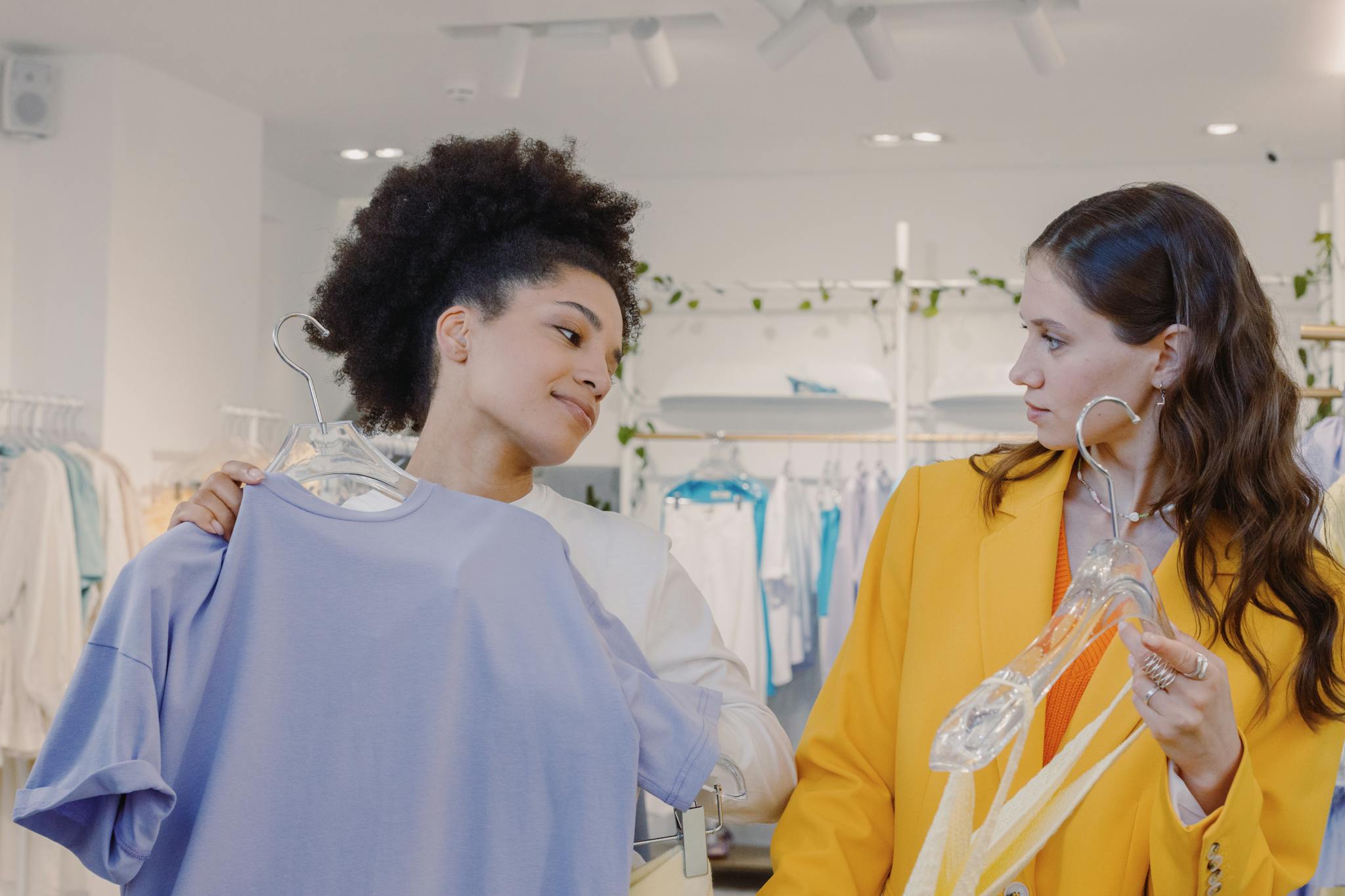Two women explore fashion choices in a modern boutique, enjoying shopping together.